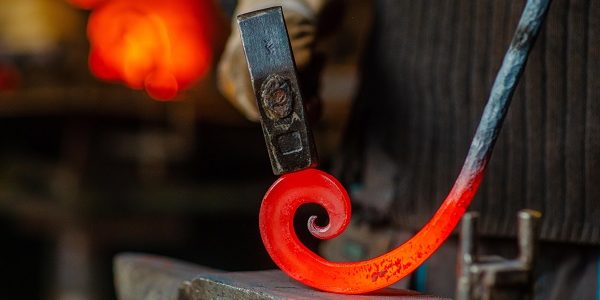 The blacksmith twists the spiral with a sledgehammer, placing a